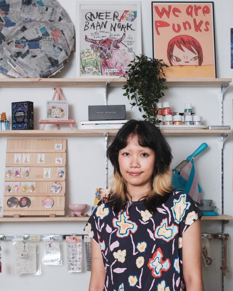 Zoom standing inside Patata Studio in Khon Kaen in front of shelves displaying zines, small objects and craft materials.