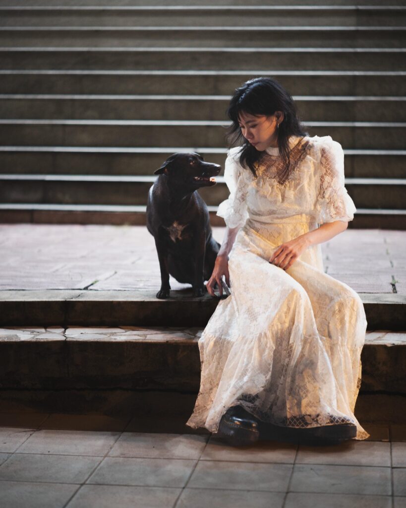 Aey Kuljira Thongkong sitting on steps beside a black dog.