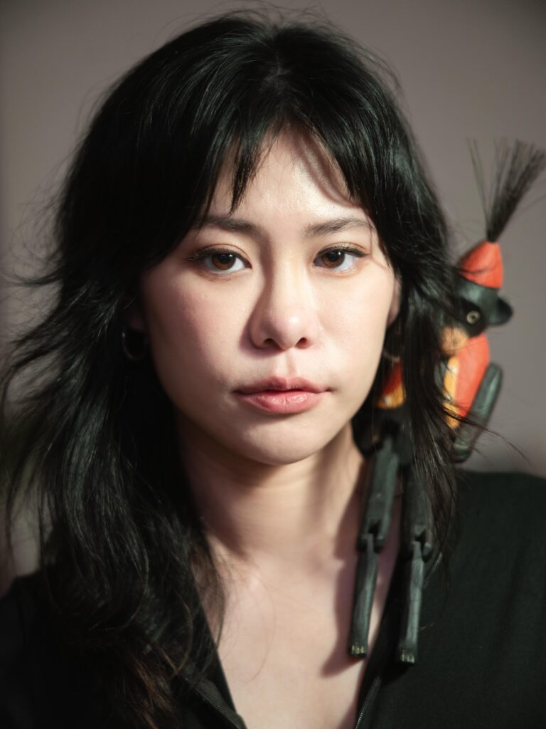 Close portrait of Aey Kuljira Thongkong with a small puppet beside her shoulder.