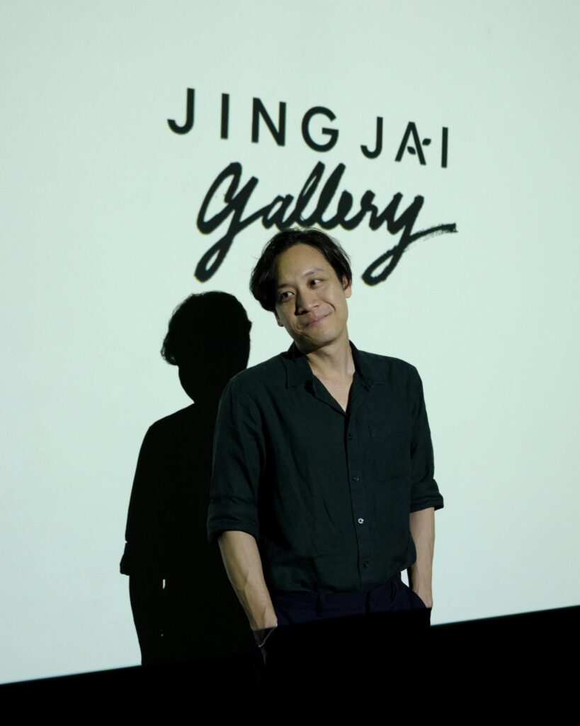 Chol Janepraphaphan standing beneath the Jing Jai Gallery sign.