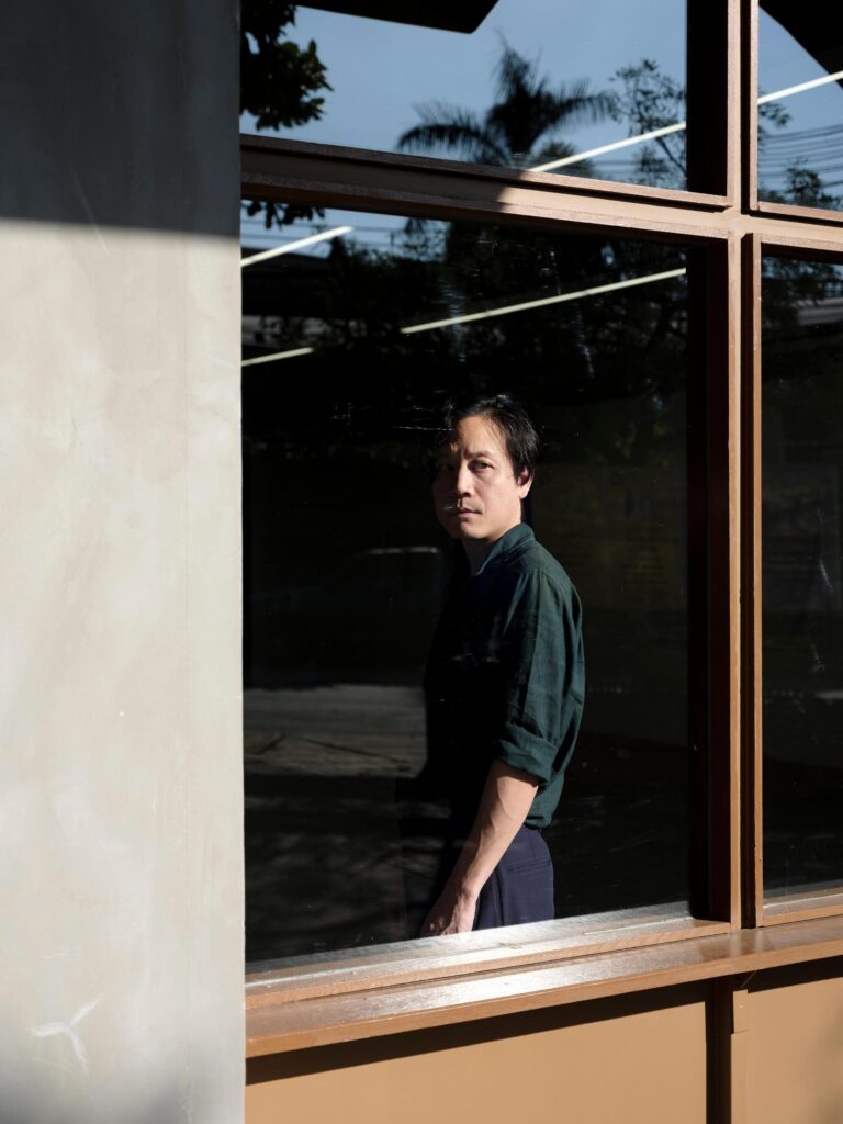 Chol Janepraphaphan seen through a large gallery window.