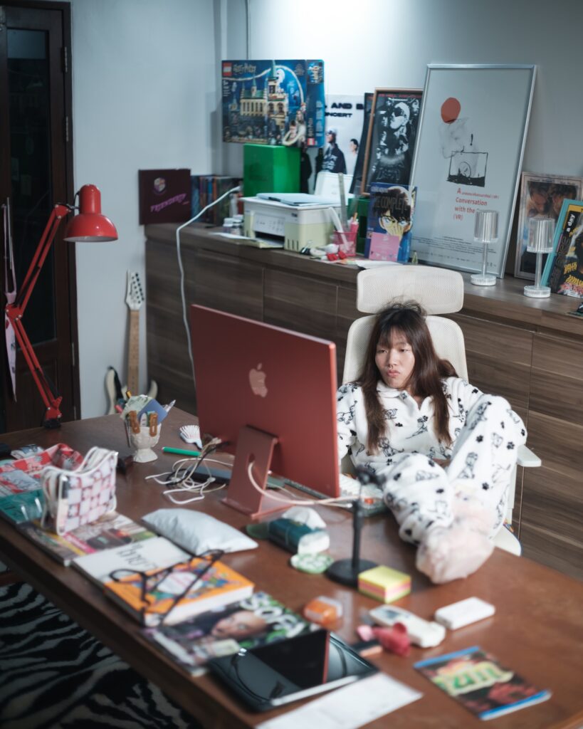 Feifei seated at a desk surrounded by books and posters