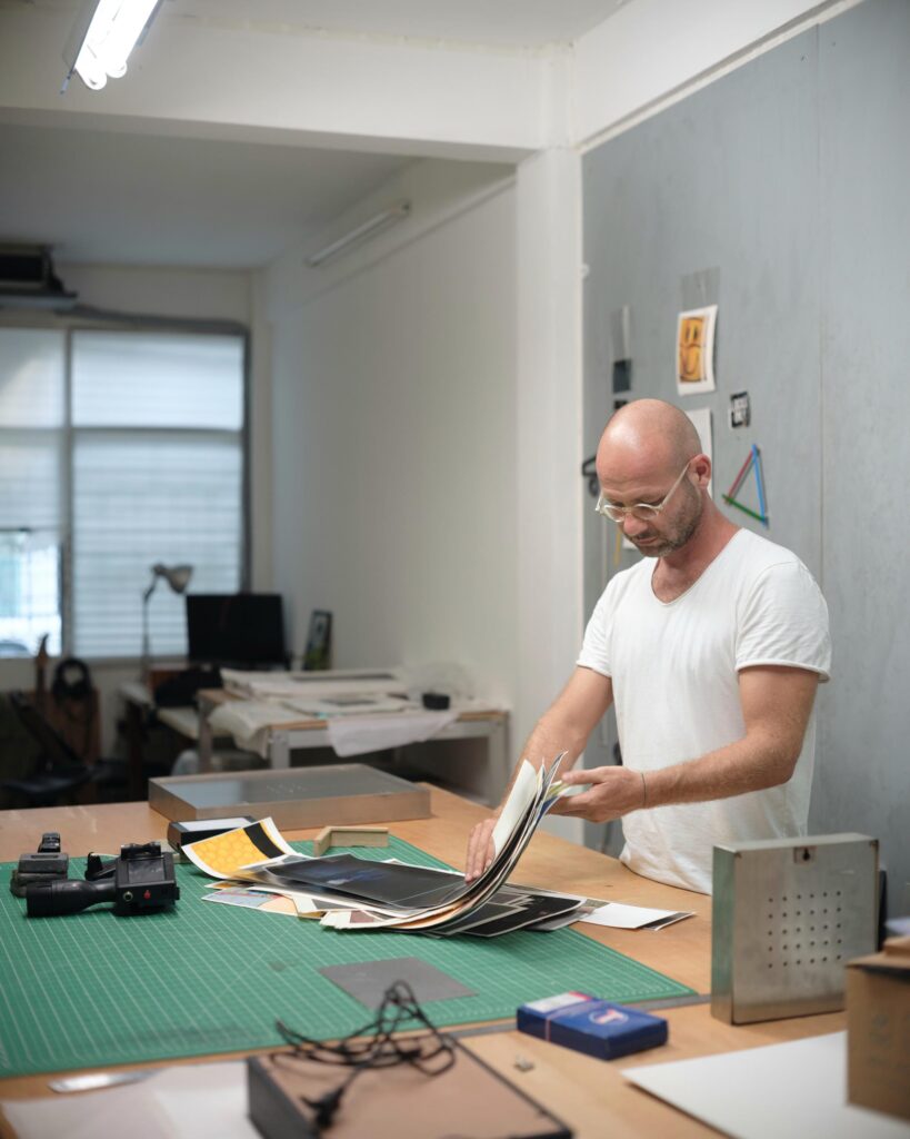 François Langella looking through prints on a studio worktable.