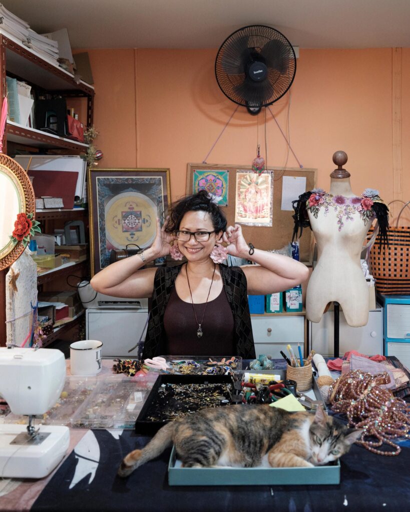 Gabriela Moriarty at a worktable with a sewing machine, art materials and a resting cat.