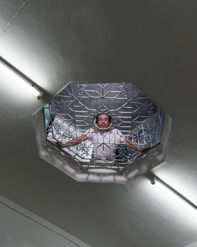 Jay Vatanakuljaras looking down through an octagonal stairwell opening with a decorative railing.