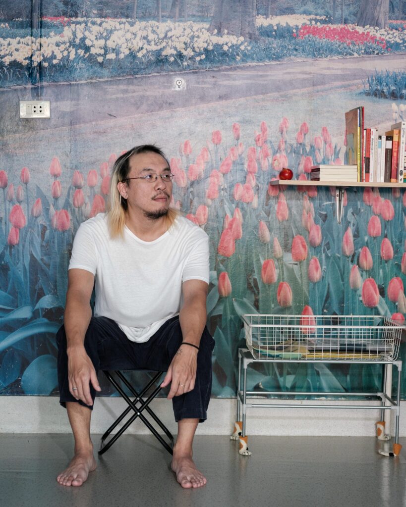 Jay Vatanakuljaras seated against a wall decorated with a tulip landscape.