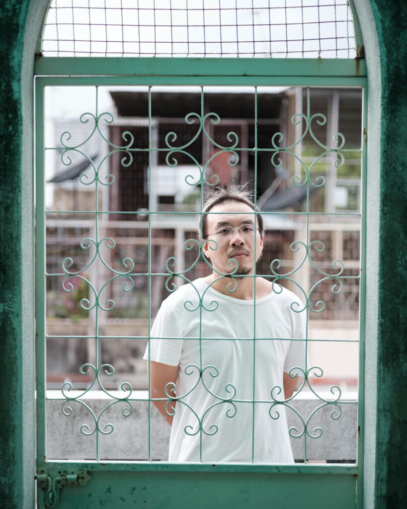 Jay Vatanakuljaras seen through a green metal gate with decorative scrollwork.