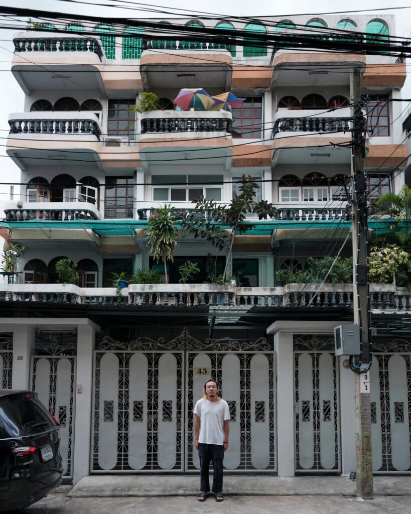 Jay Vatanakuljaras standing outside a multi-storey Bangkok shophouse.