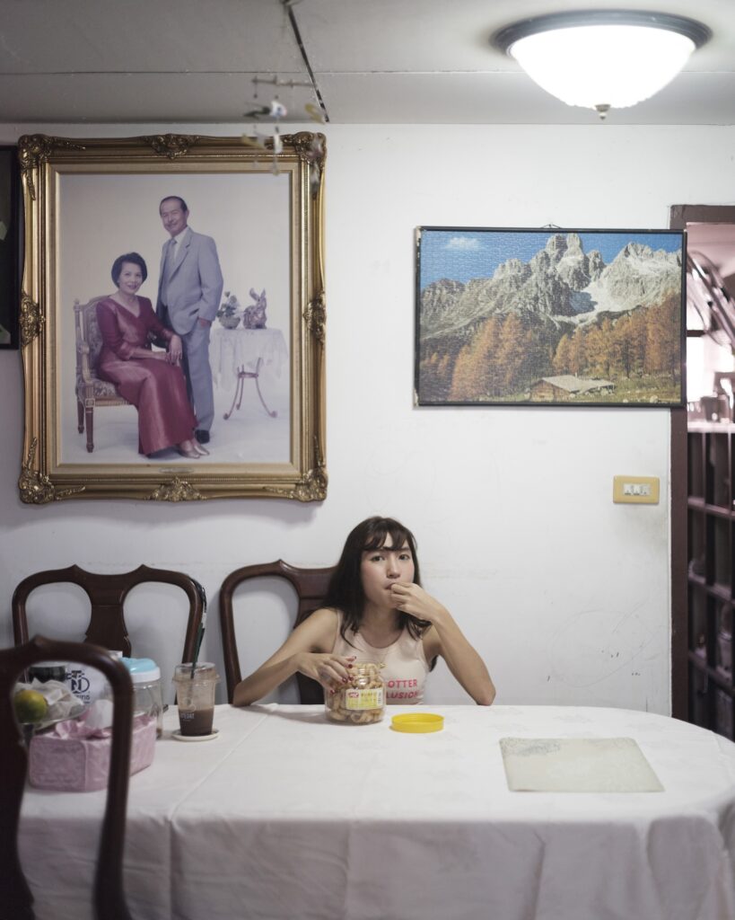 Pearamon seated at a dining table beneath framed family photographs