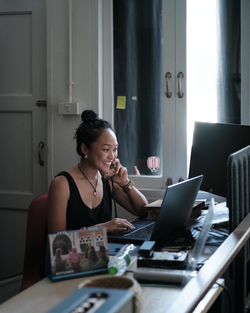Ploy Phutpheng seated at a desk with a laptop in her Bangkok studio.