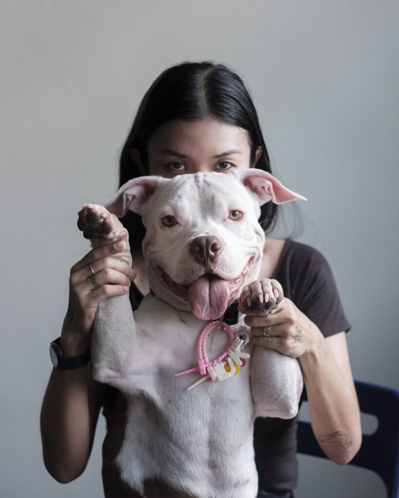 Pokchat holding her dog's front paws in a studio portrait