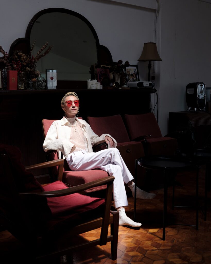 Qooqoo seated on a red chair wearing sunglasses