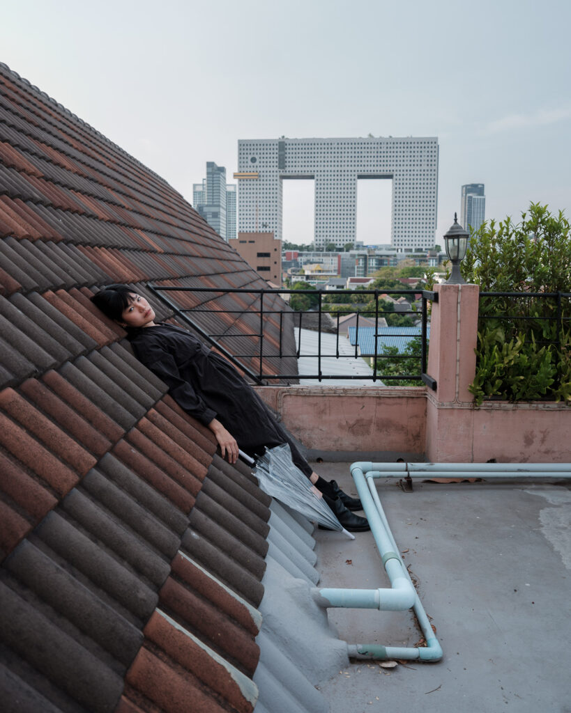 Rung reclining against a sloping rooftop with Bangkok buildings beyond
