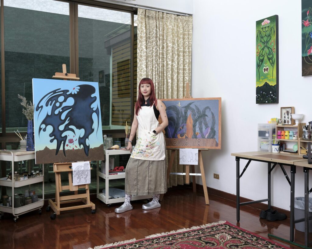 Sandy Chuchat standing between paintings on easels in her studio.