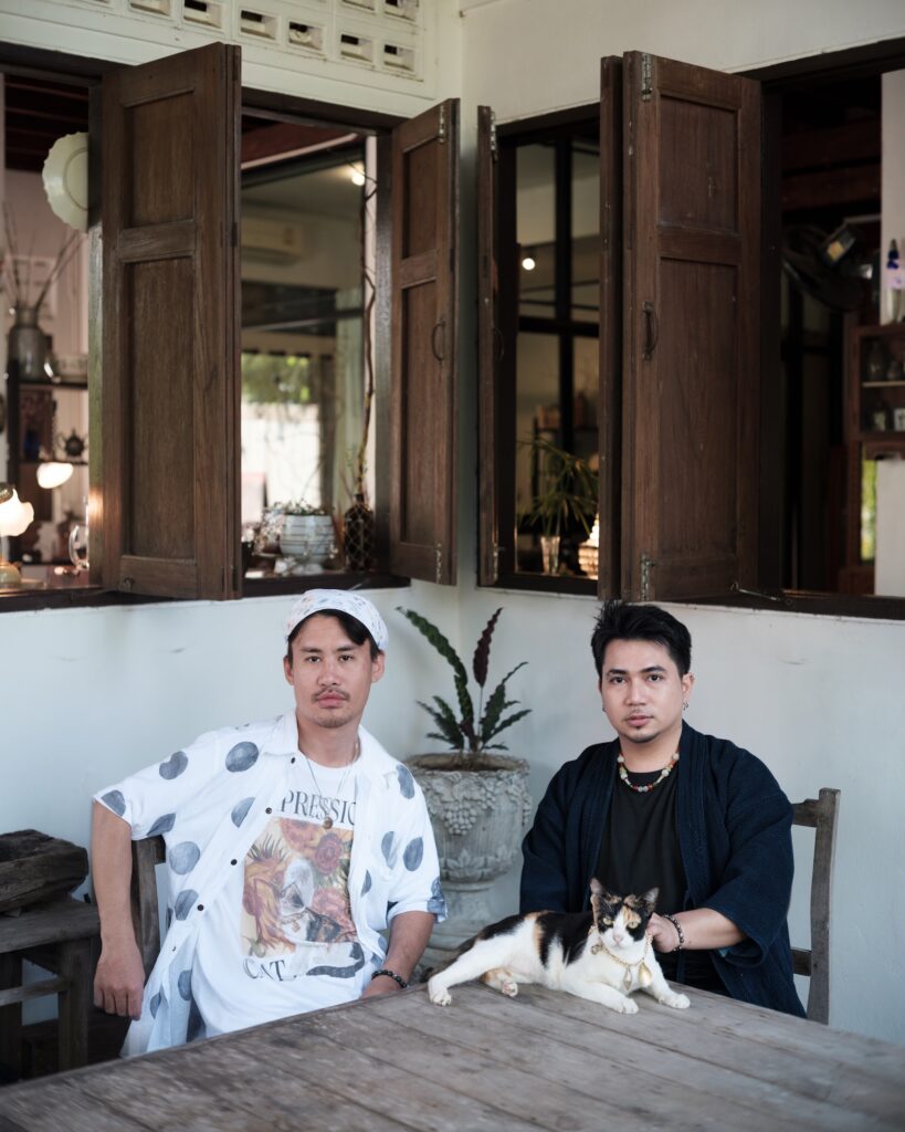 Tul and Em seated beside a cat at a wooden table