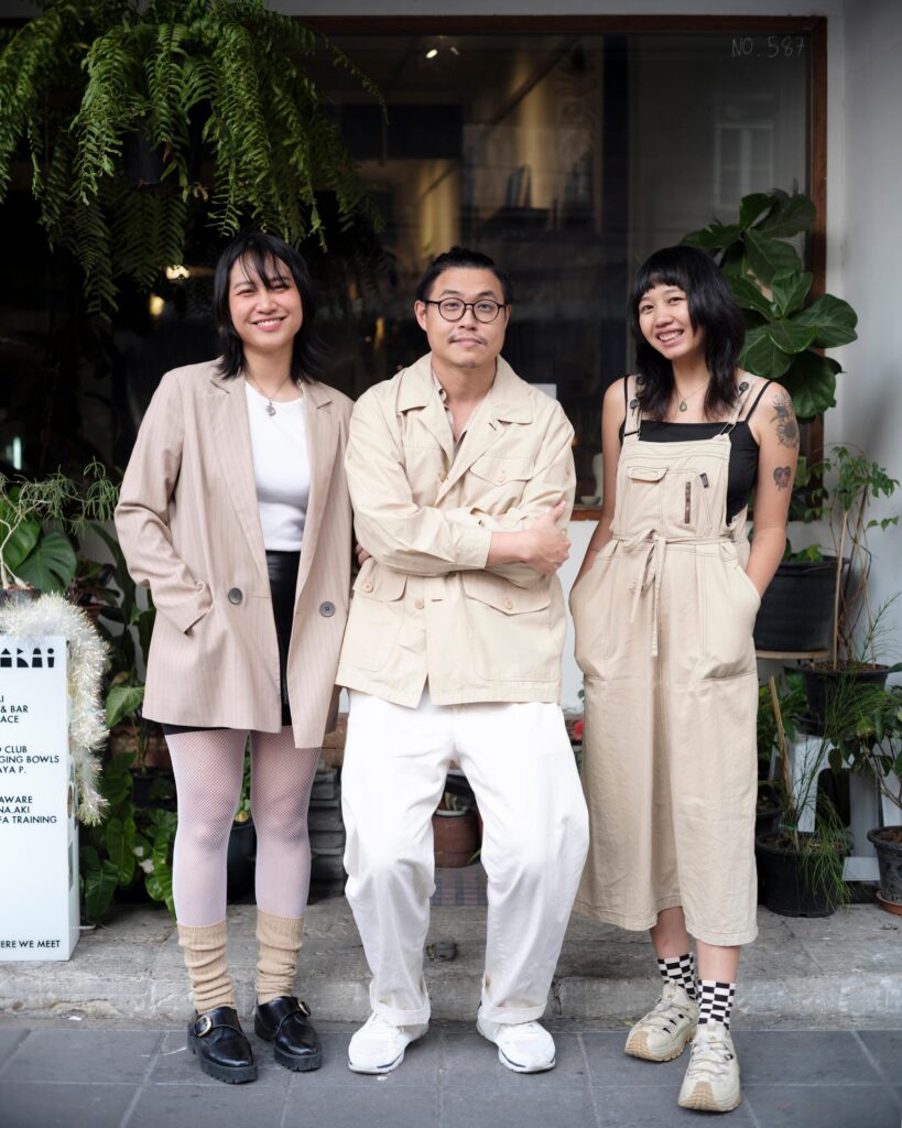 Zua, Cinema and Chalan standing together outside a Bangkok cafe.