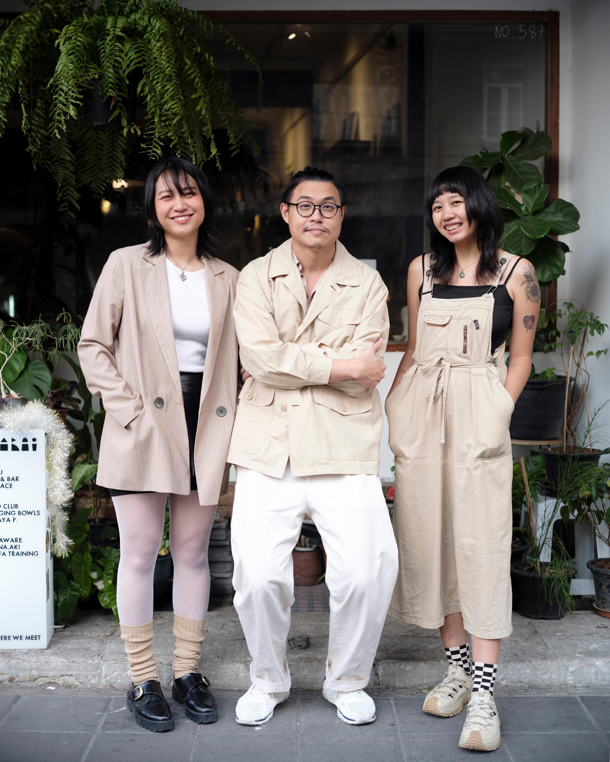 Zua, Cinema and Chalan standing together outside a Bangkok cafe.