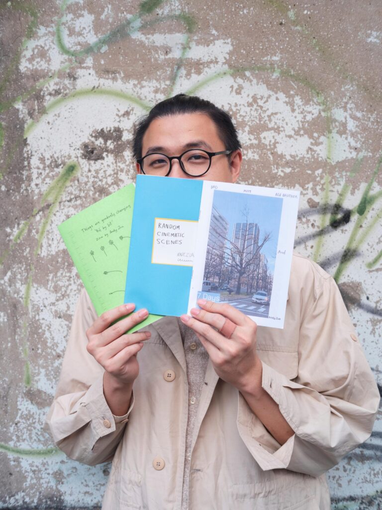 Member of Zua, Cinema and Chalan holding colourful zines in front of their face in Bangkok.