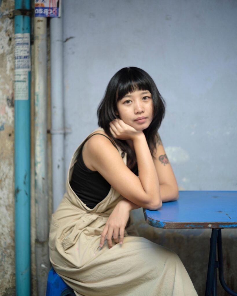 Member of Zua, Cinema and Chalan seated at a blue table in Bangkok.