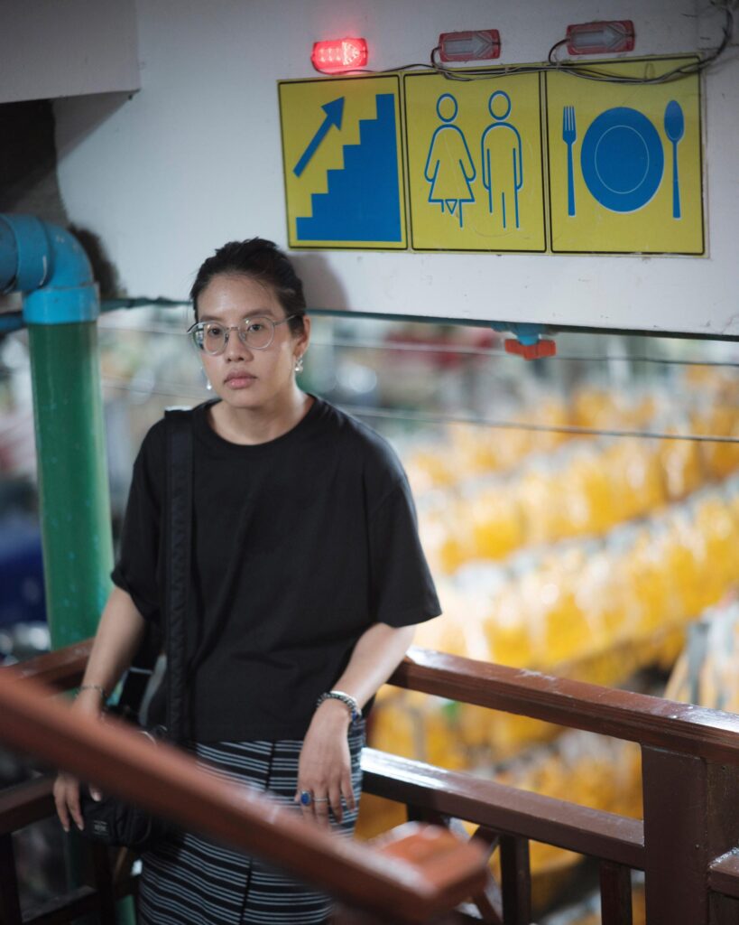 Ayre Wongchaksu leaning on a railing inside a Bangkok market.