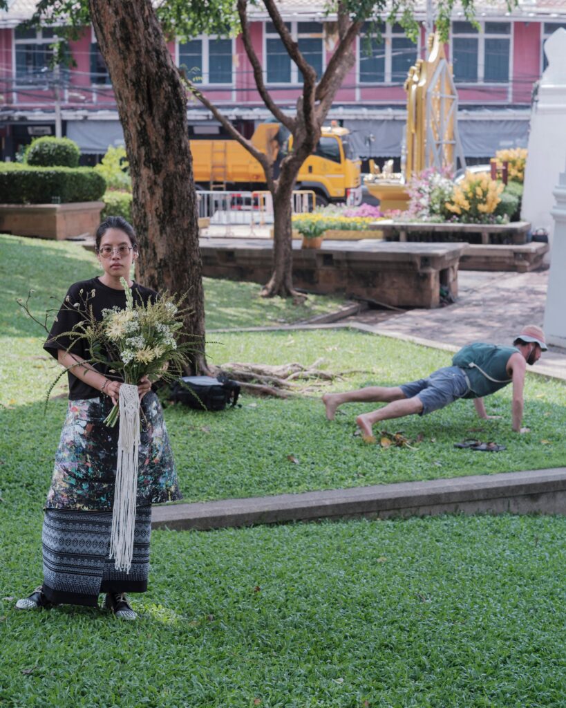 Ayre Wongchaksu holding flowers on a park lawn in Bangkok.