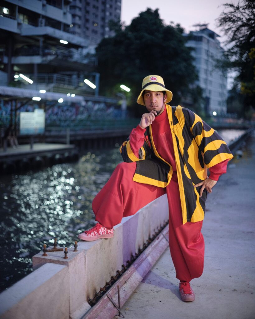 Banana Freeman balancing with one foot on a canal-side wall in Bangkok.