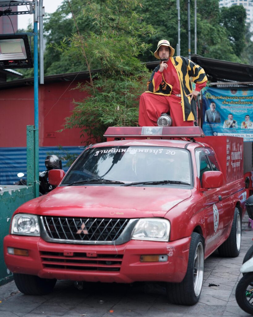 Banana Freeman sitting on the roof of a red pickup truck in Bangkok.
