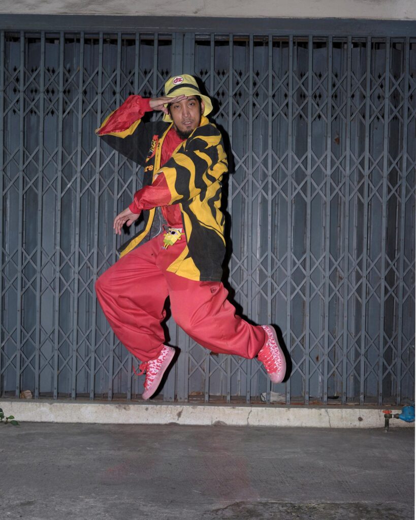 Banana Freeman jumping in front of a metal folding gate in Bangkok.