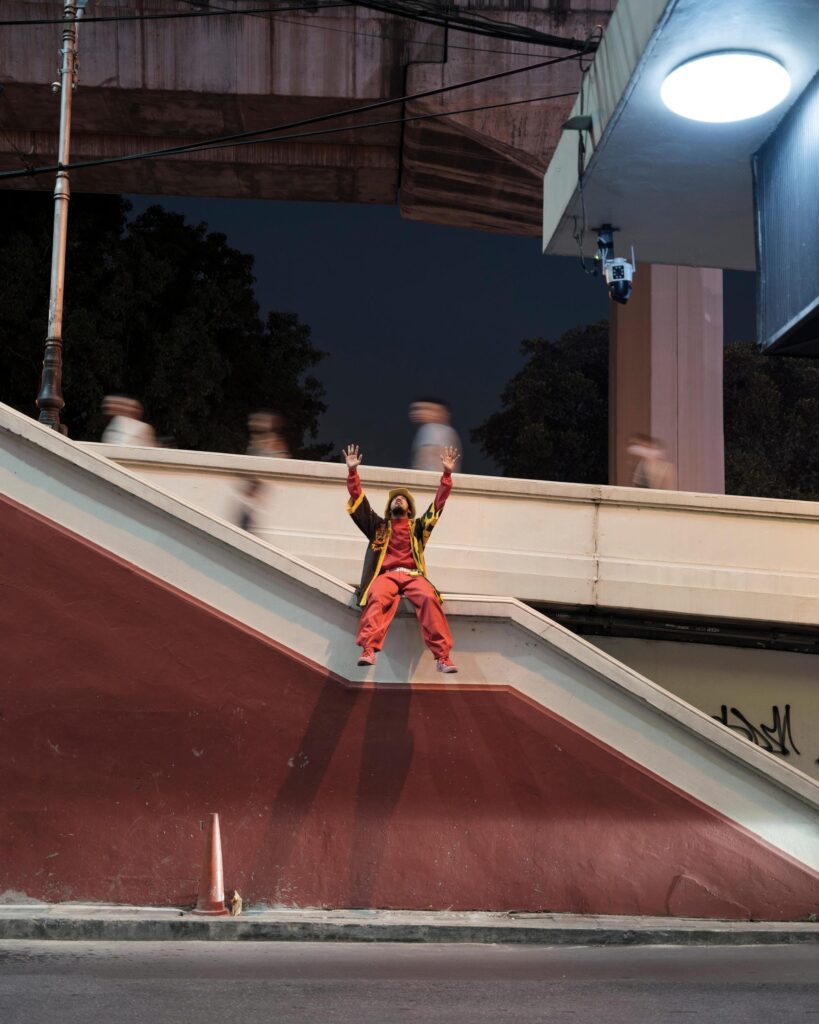 Banana Freeman standing on a stair wall outside a Bangkok building at night.