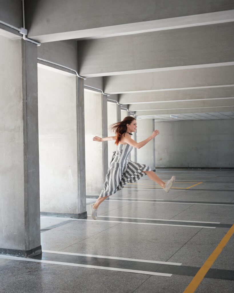 Elena Boni jumping inside an open concrete corridor in Bangkok.