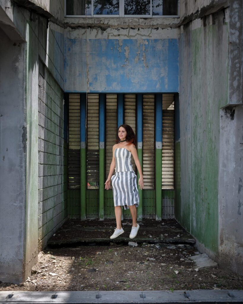 Elena Boni in a striped dress beside coloured glass panels in Bangkok.
