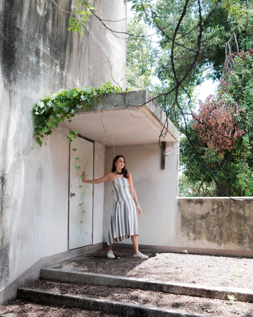 Elena Boni in a small concrete doorway surrounded by greenery in Bangkok.