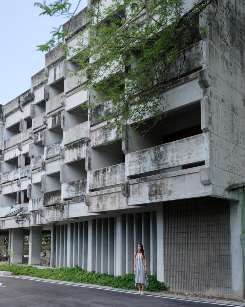 Elena Boni standing below a multi-storey concrete apartment building in Bangkok.