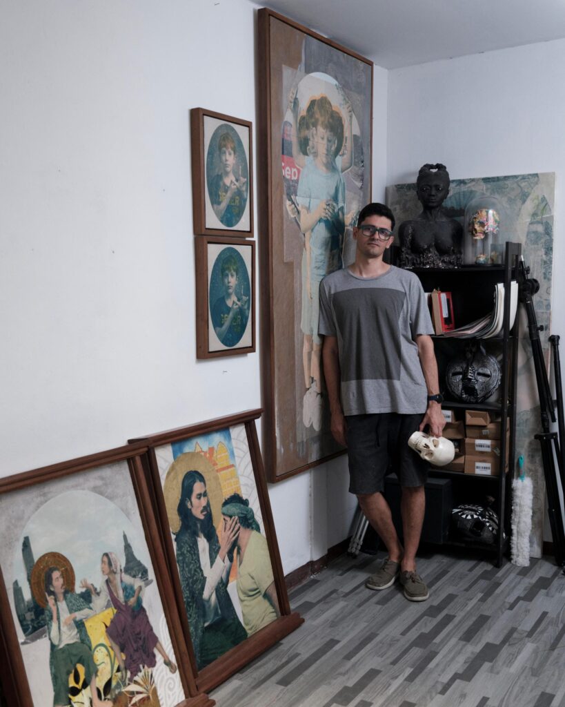 François Cambe standing among framed paintings and sculptures in his Bangkok studio.