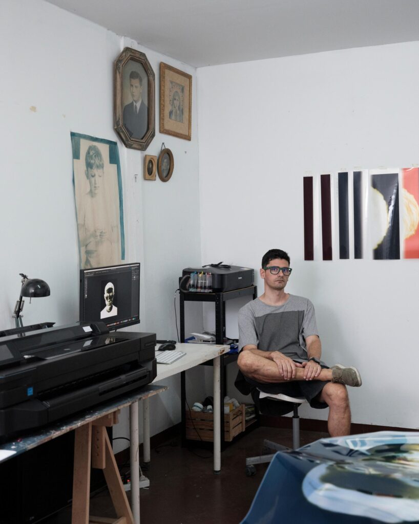 François Cambe seated beside a printing press in his Bangkok studio.