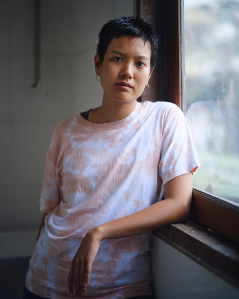 Hutsama Juntaratana in a pale patterned shirt beside a window in Bangkok.