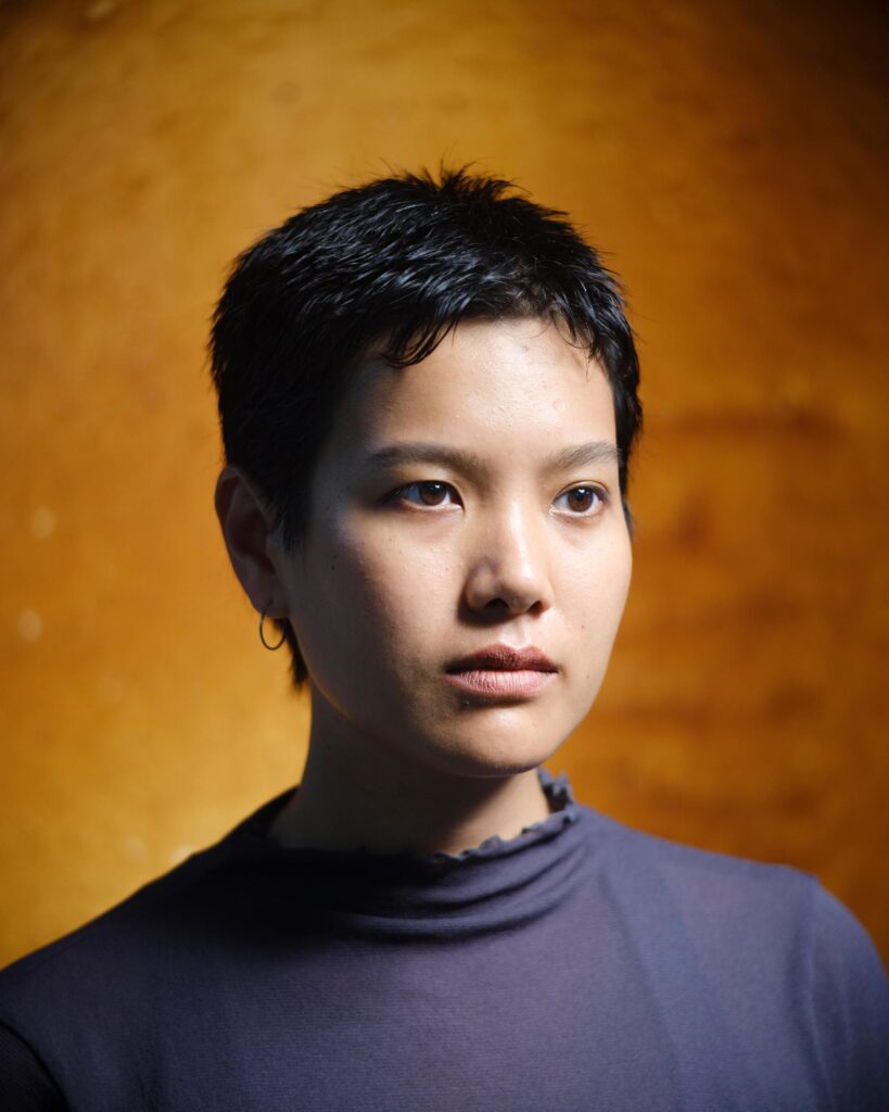 Close portrait of Hutsama Juntaratana against a gold-toned wall in Bangkok.