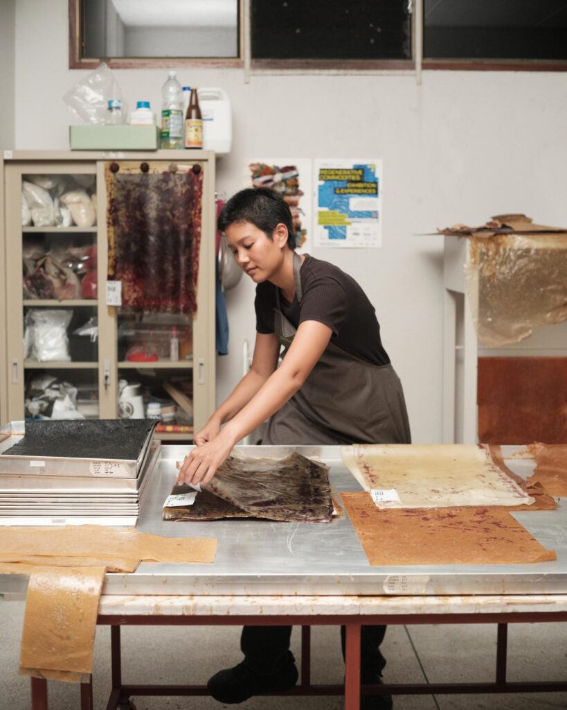 Hutsama Juntaratana working at a large workshop table in Bangkok.