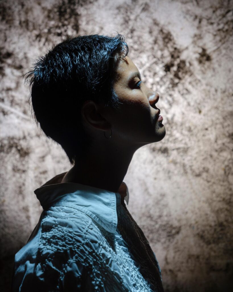 Side profile of Hutsama Juntaratana in directional light against a textured wall in Bangkok.