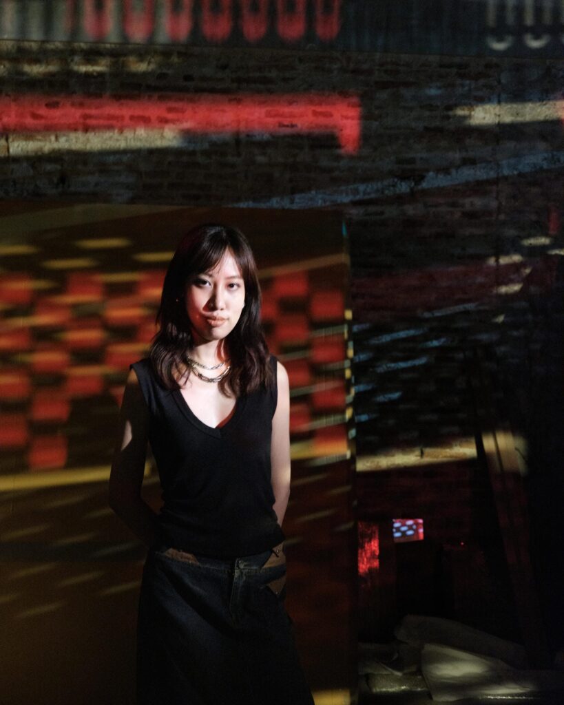 Issiree Shereen Sarntisart with colourful projected patterns across the room in Bangkok.