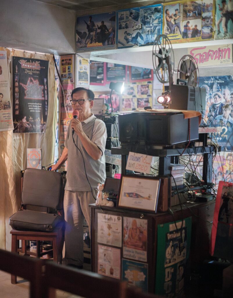 Manit Worachat beside a vintage film projector and movie posters in his Lampang museum.