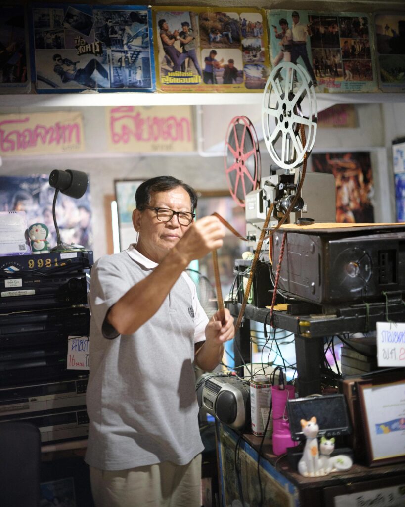 Manit Worachat handling a reel on a vintage film projector in his Lampang museum.