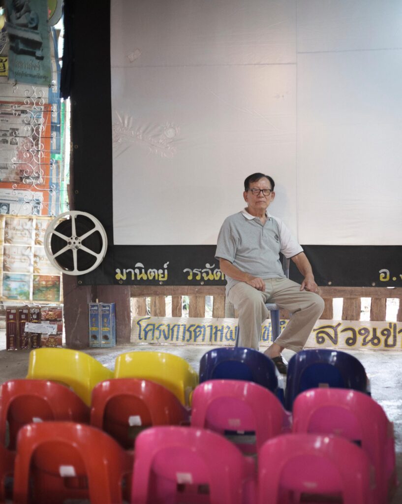 Manit Worachat seated behind rows of colourful plastic cinema chairs in his Lampang museum.