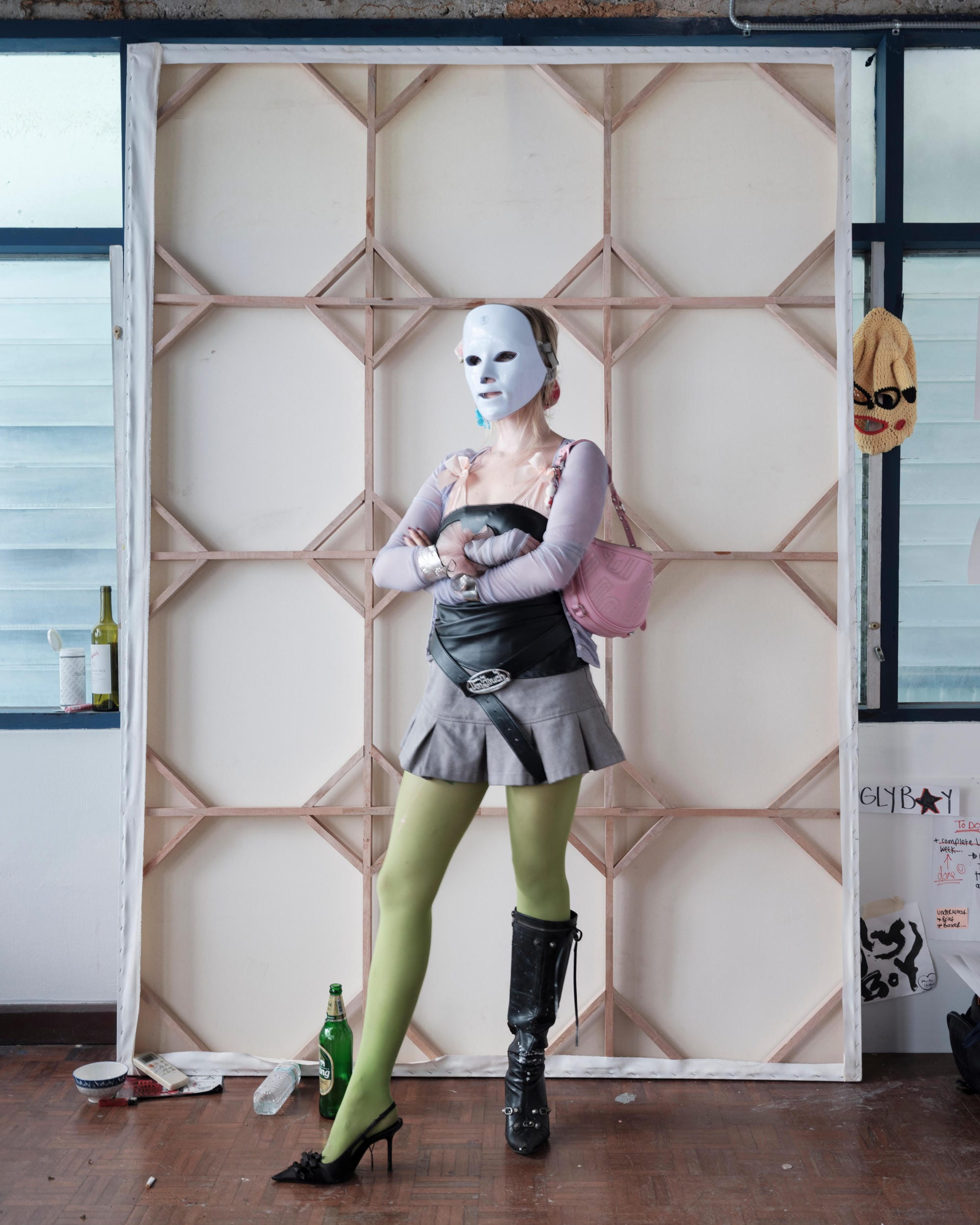 Mascha Serga wearing a white mask in front of a stretched canvas in her Bangkok studio.