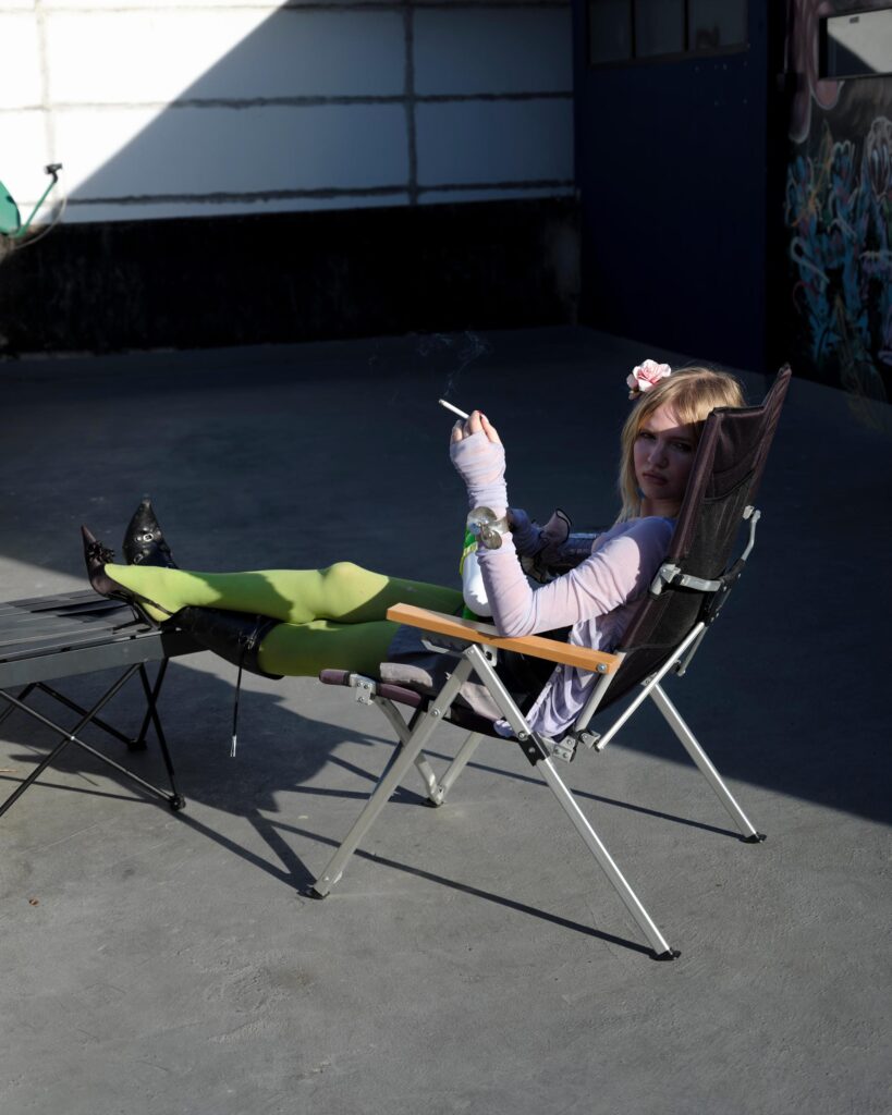 Mascha Serga reclining on a folding chair in sunlight on a Bangkok rooftop.