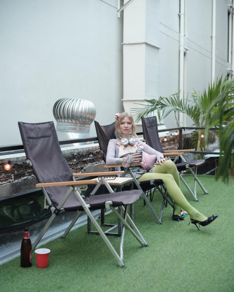 Mascha Serga reclining in a folding chair on a Bangkok rooftop terrace.