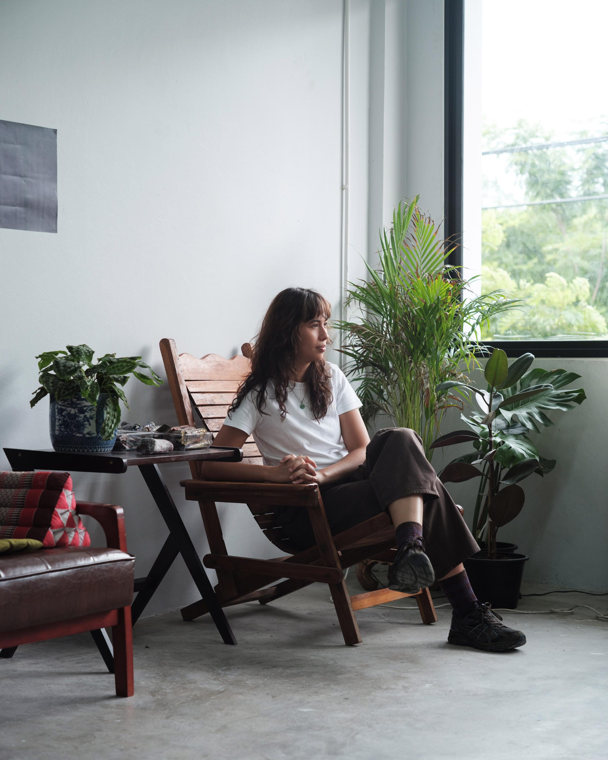 Natalie Sasi Organ seated beside plants and a window in her Bangkok studio.