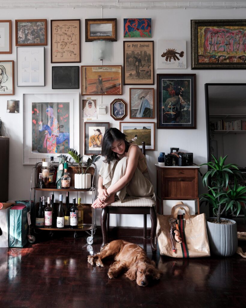 Pahparn Sirima seated with a dog in an art-filled Bangkok apartment.