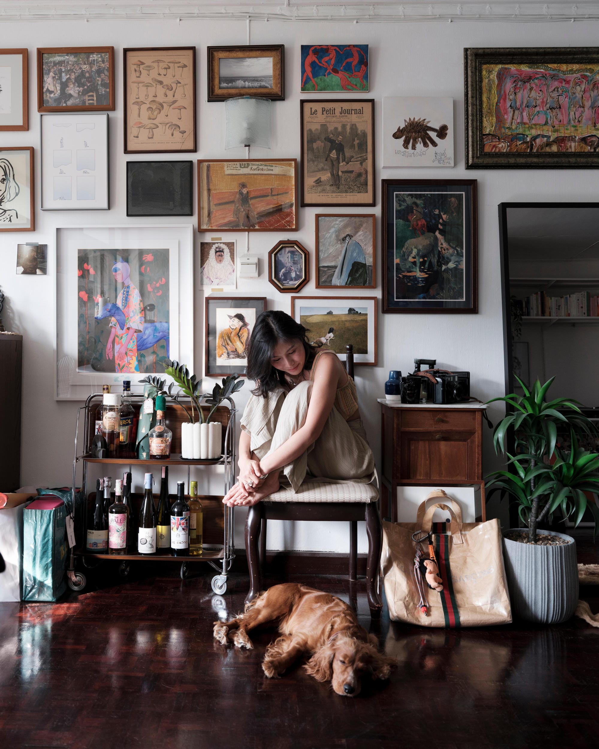 Pahparn Sirima seated with a dog in an art-filled Bangkok apartment.