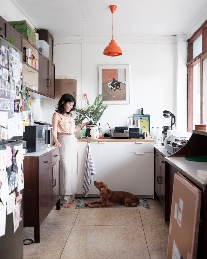 Pahparn Sirima standing in her Bangkok kitchen while a dog lies on the floor.